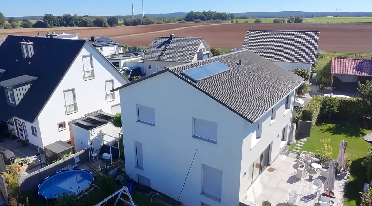 Weißes Einfamilienhaus mit Solardach am Feldrand