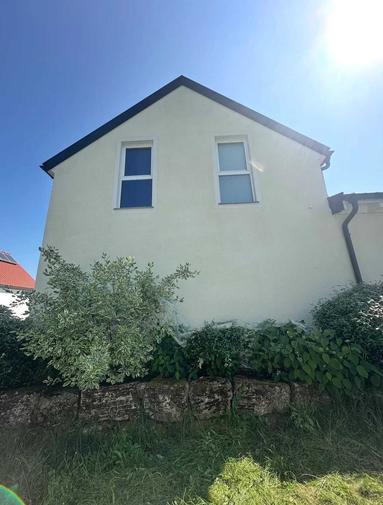 Gereinigter Hausgiebel über einer Natursteinmauer