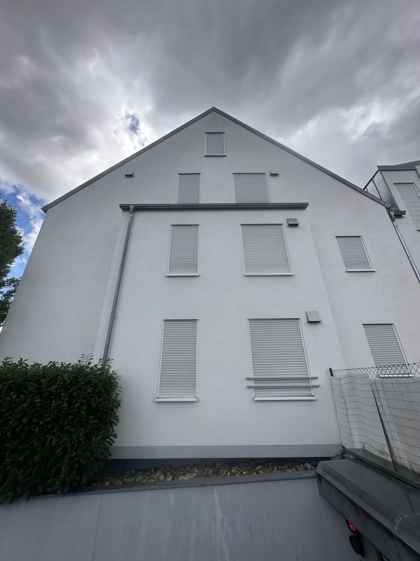Gereinigte weiße Giebelfassade vor dramatischem Himmel