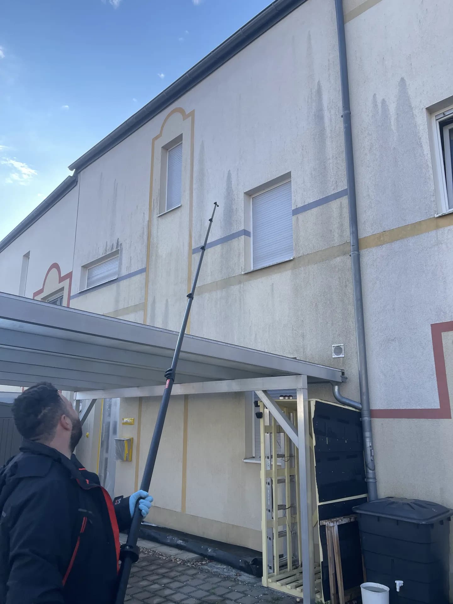 Techniker reinigt Zierfassade vom Carport aus