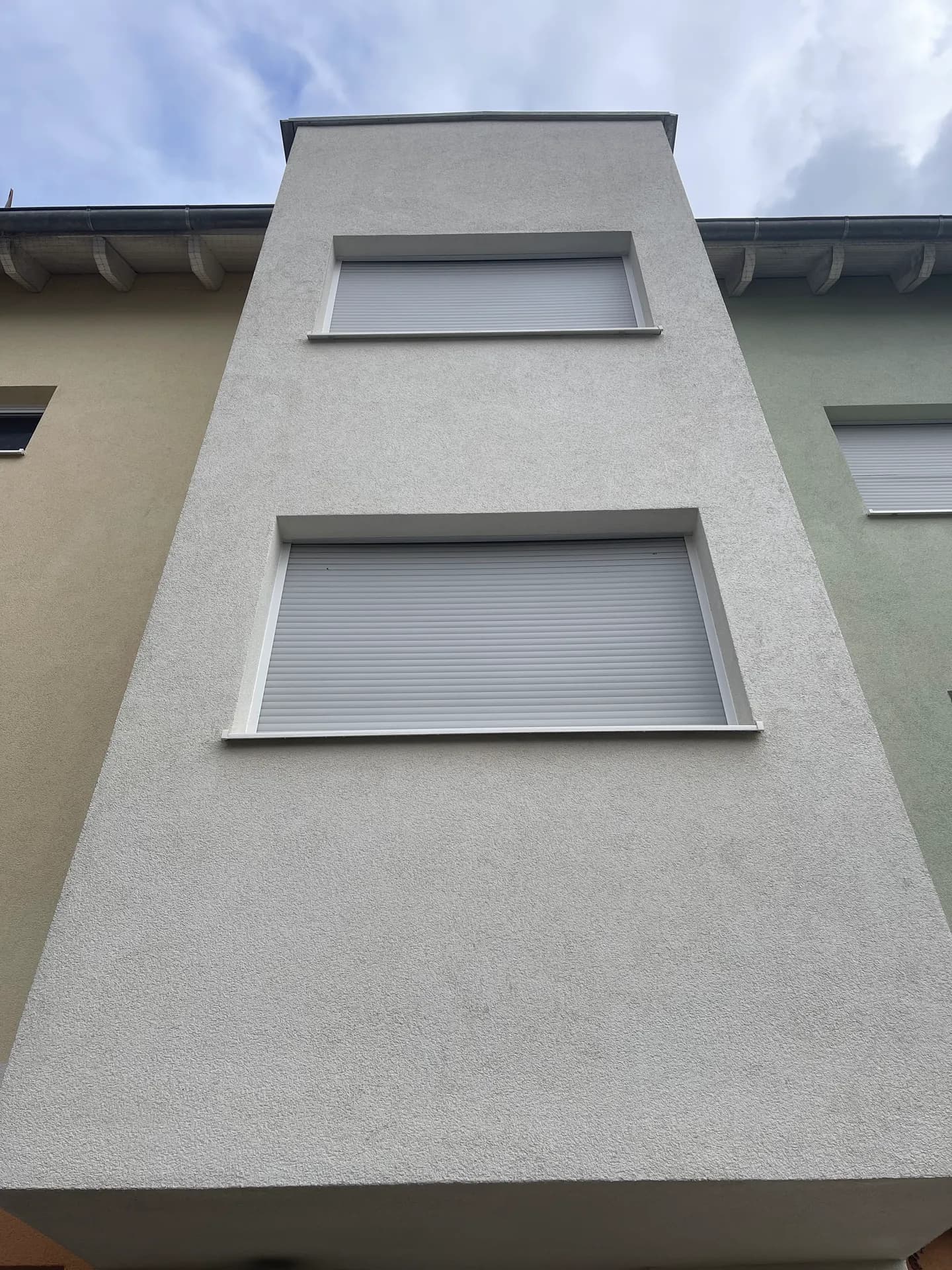 Gereinigter Fassadenturm mit Rollläden unter blauem Himmel